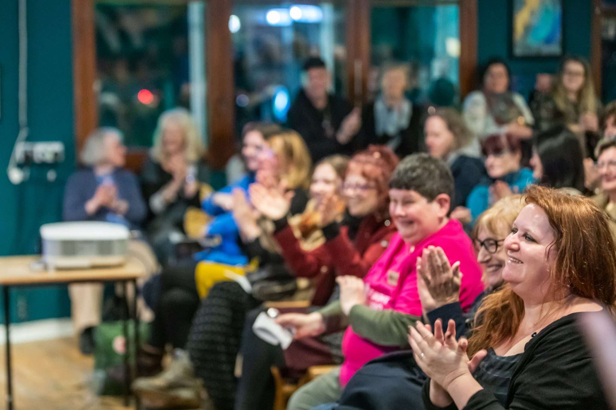 Audience in a packed room applauding.