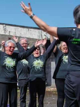 Freedom Of Mind Community Choir members smiling, singing and stretching out their arms