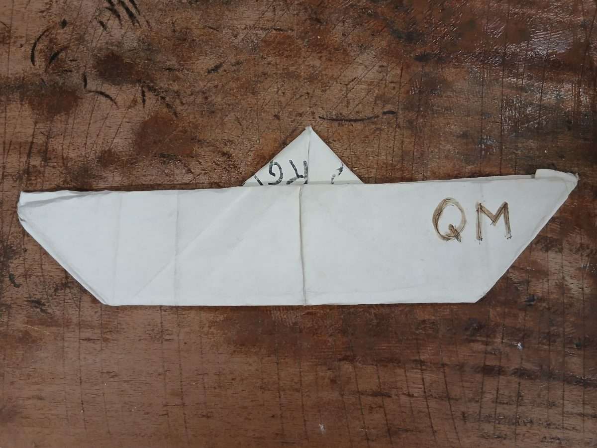 Paper boat with the initials QM on it.